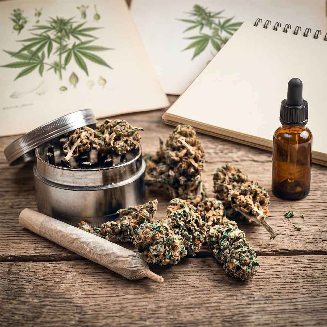 Cannabis-Blüten neben einem Grinder, Joint und einer CBD-Öl-Flasche auf einem Holztisch. Das ideale Titelbild für einen Schweizer Hanf-Blog.